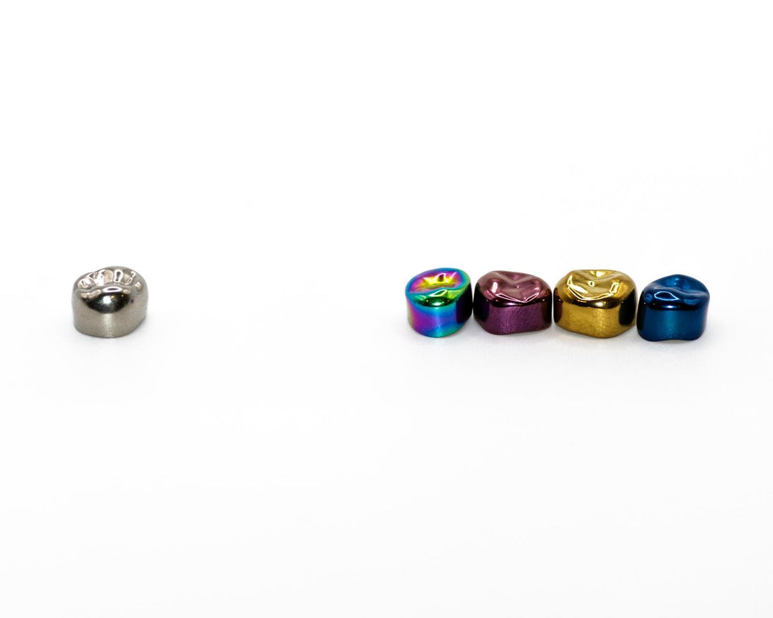Traditional silver stainless steel crown next to Prismo colored crowns